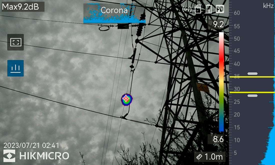 Captura da câmera: descarga parcial classificada como corona em rede aérea, com o ponto de emissão marcado sobre a imagem real.